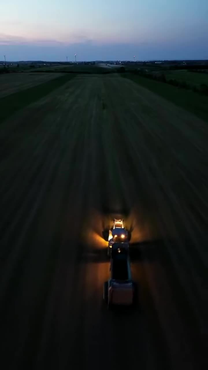 Tracteur dans un champ au crépuscule, vue de drone